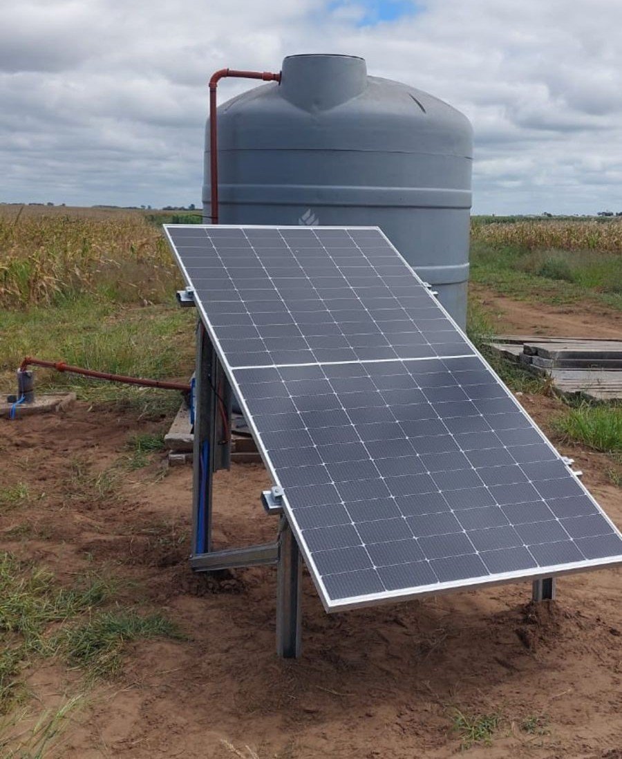 Imagen ilustrativa de paneles solares junto a un tanque de agua rural.